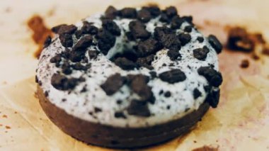 Oeo bisküvileriyle süslenmiş çikolatalı çörekler. Donutlar doğal çikolatayla süslenmiş bir kağıdın üzerinde. Makro ve kaydırma atışı. Fırın ve yemek konsepti. Çeşitli renkli çörekler. Çikolata.