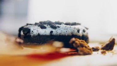 Oeo bisküvileriyle süslenmiş çikolatalı çörekler. Donutlar doğal çikolatayla süslenmiş bir kağıdın üzerinde. Makro ve kaydırma atışı. Fırın ve yemek konsepti. Çeşitli renkli çörekler. Çikolata.