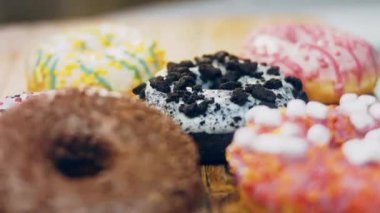 Çikolata, marşmelov ve retro pişirme tepsisindeki şekerli çörekler. Donutlar doğal çikolatayla süslenmiş bir kağıdın üzerinde. Makro ve kaydırma atışı. Çeşitli renkli çörekler. Çikolata, pembe, mavi çörekler