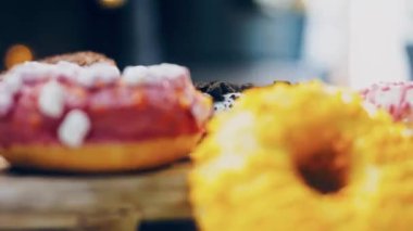 Çikolata, marşmelov ve retro pişirme tepsisindeki şekerli çörekler. Donutlar doğal çikolatayla süslenmiş bir kağıdın üzerinde. Makro ve kaydırma atışı. Çeşitli renkli çörekler. Çikolata, pembe, mavi çörekler