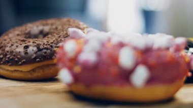 Çikolata, marşmelov ve retro pişirme tepsisindeki şekerli çörekler. Donutlar doğal çikolatayla süslenmiş bir kağıdın üzerinde. Makro ve kaydırma atışı. Çeşitli renkli çörekler. Çikolata, pembe, mavi çörekler