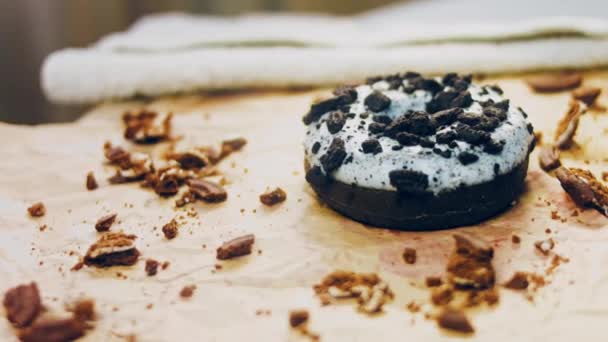 巧克力甜甜圈 上面装饰着一些意大利饼干 甜甜圈在用天然巧克力装饰的纸上 宏观和滑翔机射击 面包店和食品概念 各种彩色甜甜圈 巧克力味的 — 图库视频影像