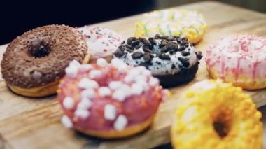 Çikolata, marşmelov ve retro pişirme tepsisindeki şekerli çörekler. Donutlar doğal çikolatayla süslenmiş bir kağıdın üzerinde. Makro ve kaydırma atışı. Çeşitli renkli çörekler. Çikolata, pembe, mavi çörekler