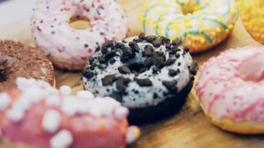 Çikolata, marşmelov ve retro pişirme tepsisindeki şekerli çörekler. Donutlar doğal çikolatayla süslenmiş bir kağıdın üzerinde. Makro ve kaydırma atışı. Çeşitli renkli çörekler. Çikolata, pembe, mavi çörekler