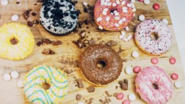 Çikolata, marşmelov ve retro pişirme tepsisindeki şekerli çörekler. Donutlar doğal çikolatayla süslenmiş bir kağıdın üzerinde. Makro ve kaydırma atışı. Çeşitli renkli çörekler. Çikolata, pembe, mavi çörekler