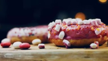 Çikolata, marşmelov ve retro pişirme tepsisindeki şekerli çörekler. Donutlar doğal çikolatayla süslenmiş bir kağıdın üzerinde. Makro ve kaydırma atışı. Çeşitli renkli çörekler. Çikolata, pembe, mavi çörekler