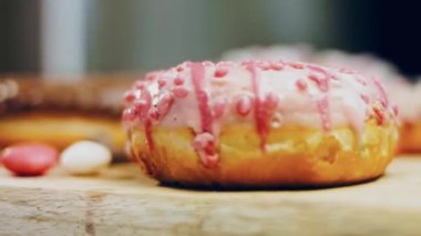 Çikolata, marşmelov ve retro pişirme tepsisindeki şekerli çörekler. Donutlar doğal çikolatayla süslenmiş bir kağıdın üzerinde. Makro ve kaydırma atışı. Çeşitli renkli çörekler. Çikolata, pembe, mavi çörekler