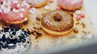 Çikolata, marşmelov ve retro pişirme tepsisindeki şekerli çörekler. Donutlar doğal çikolatayla süslenmiş bir kağıdın üzerinde. Makro ve kaydırma atışı. Çeşitli renkli çörekler. Çikolata, pembe, mavi çörekler