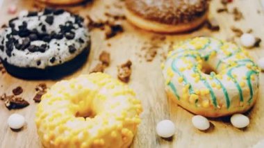 Çikolata, marşmelov ve retro pişirme tepsisindeki şekerli çörekler. Donutlar doğal çikolatayla süslenmiş bir kağıdın üzerinde. Makro ve kaydırma atışı. Çeşitli renkli çörekler. Çikolata, pembe, mavi çörekler