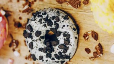 Çikolata, marşmelov ve retro pişirme tepsisindeki şekerli çörekler. Donutlar doğal çikolatayla süslenmiş bir kağıdın üzerinde. Makro ve kaydırma atışı. Çeşitli renkli çörekler. Çikolata, pembe, mavi çörekler