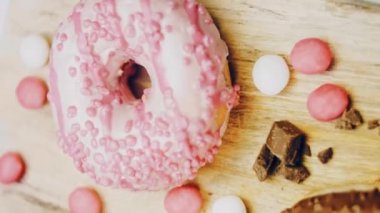 Çikolata, marşmelov ve retro pişirme tepsisindeki şekerli çörekler. Donutlar doğal çikolatayla süslenmiş bir kağıdın üzerinde. Makro ve kaydırma atışı. Çeşitli renkli çörekler. Çikolata, pembe, mavi çörekler