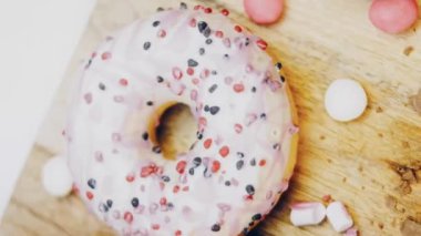 Çikolata, marşmelov ve retro pişirme tepsisindeki şekerli çörekler. Donutlar doğal çikolatayla süslenmiş bir kağıdın üzerinde. Makro ve kaydırma atışı. Çeşitli renkli çörekler. Çikolata, pembe, mavi çörekler