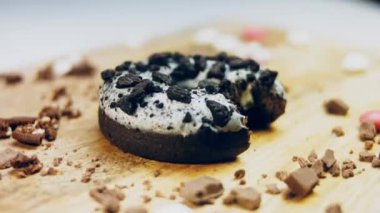 Donut 'ın ağız şeklinde bir ısırığı var. Oeo bisküvileriyle süslenmiş çikolatalı çörekler. Donutlar doğal çikolatayla süslenmiş bir kağıdın üzerinde. Makro ve kaydırma atışı. Fırın ve gıda konsepti