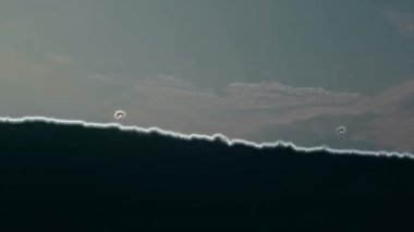 Paraglider soaring against the backdrop of a sunny blue sky. Bottom view.