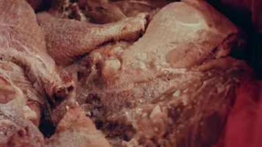 Eldivenli ellerin yakın plan görüntüsü tavuk bacağını bir kutudan ayrı plastik poşetlere paketliyor. Evde daha fazla kullanılmak üzere dondurulmuş etin süreci. Işık oynatma ile 4k video