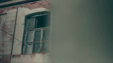 İçler acısı durumdaki çok eski bir ev. Kırılmış ve tahrip edilmiş pencereler.