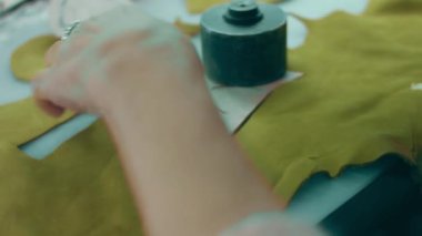 Deri atölyesinde dikiş makinesi çalışıyor. Elleri ayakkabı için deri detaylar üzerinde çalışıyor. Ayakkabı fabrikasında dikiş makinesiyle kadın eli makro çekim..