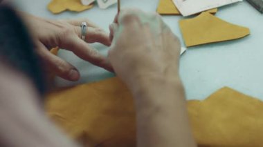 Deri atölyesinde dikiş makinesi çalışıyor. Elleri ayakkabı için deri detaylar üzerinde çalışıyor. Ayakkabı fabrikasında dikiş makinesiyle kadın eli makro çekim..