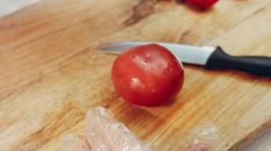4K 'de kesme tahtasındaki bıçakla deri domateslerinin soyulduğu yakın plan..