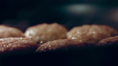 Juicy delicious meat cutlets are fried in oil on black pan. Simple home cooking
