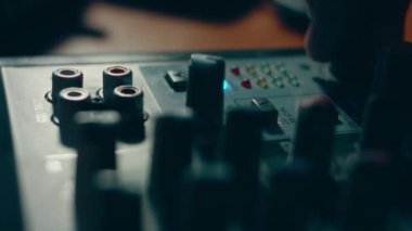 Ses karıştırma konsolunu ayarlayan parmaklar yakın plan. Ses üretimi için kayıt stüdyosunda mikser konsolu. Zayıf ışık.