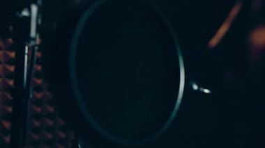 Profesyonel mikrofonlu yakışıklı rap şarkıcısının portresi modern stüdyoda şarkı söylüyor. Müzik prodüksiyonu. Zayıf ışık.