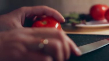 Kadın eli mutfak bıçağıyla kesme tahtasında taze domates kesiyor. Sağlıklı beslenme