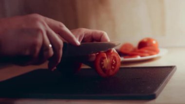 Kadın eli mutfak bıçağıyla kesme tahtasında taze domates kesiyor. Sağlıklı beslenme