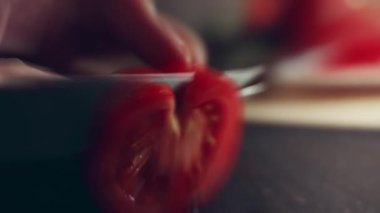 Kadın eli mutfak bıçağıyla kesme tahtasında taze domates kesiyor. Sağlıklı beslenme