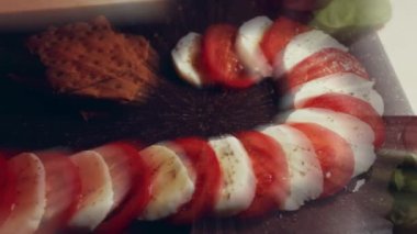 Caprese - İtalyan ulusal yemeği. Noel şeker kamışı şeklinde dilimlenmiş domates ve mozarella. Fesleğen ve zeytinyağıyla servis edilir. Yavaş çekim.