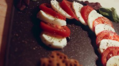 Caprese - İtalyan ulusal yemeği. Noel şeker kamışı şeklinde dilimlenmiş domates ve mozarella. Fesleğen ve zeytinyağıyla servis edilir. Yavaş çekim.