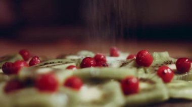 Sulu taze kivi dilimleri ve kırmızı frenk üzümü siyah mermer bir kesim tahtasının üzerinde noel ağacı şeklinde dizilmiş. Noel tatili için yemek. Sağlıklı atıştırmalıklar. Zaman Uygulaması.