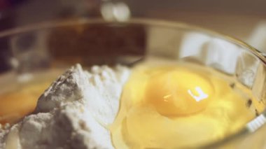 Undan elde edilen hamur işlemini kapat. Tavuk yumurtası ve cam kasede bir yığın beyaz un. Ravioli hazırlama işlemi. 4K video. Yavaş çekim.