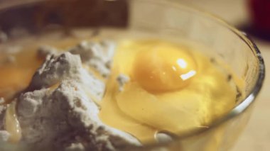 Undan elde edilen hamur işlemini kapat. Tavuk yumurtası ve cam kasede bir yığın beyaz un. Ravioli hazırlama işlemi. 4K video. Yavaş çekim.