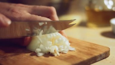 Kadın eli, soğanın yarısını tahta tahtada bıçakla küp küp doğruyor. Evde ravioli hazırlama süreci. 4 K video.