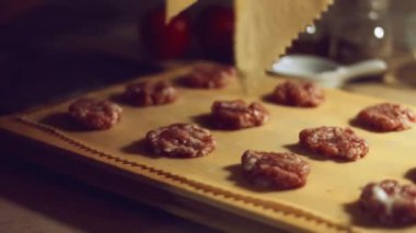 Eti hamurla kaplayan kadın eli yakın plan. Tipik bir İtalyan yemeği olan ravioli hazırlamak, eski İtalyan geleneğine göre ev yapımı. 4K video