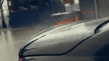 Beyaz köpükle kaplı ve su tabancasından sıçramış lüks araba yıkama işlemi. Parlak araba dış yüzeyine köpük saçılıyor. Güzel bir ortam. 4K video.