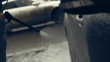 Beyaz köpükle kaplı ve su tabancasından sıçramış lüks araba yıkama işlemi. Parlak araba dış yüzeyine köpük saçılıyor. Güzel bir ortam. 4K video.