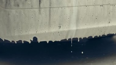 Beyaz köpükle kaplı ve su tabancasından sıçramış lüks araba yıkama işlemi. Parlak araba dış yüzeyine köpük saçılıyor. Güzel bir ortam. 4K video.