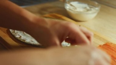 İnce, renkli krepler. Kadınların, somon dilimlerini, ahşap bir tahtanın üzerinde krem peynirle yağlanmış kırmızı krep ile doldurdukları yakın plan. Krepi yuvarlıyorum..