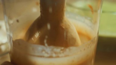 Malzemeleri el blenderiyle karıştırmadan önce krep hamuruna havuç eklemek. Renkli krep hazırlama süreci. 4K video.