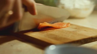 Ahşap bir tahtada taze somon filetosu dilimleyen kadın elinin yakın çekimi. 4K video, zaman ayarlı.