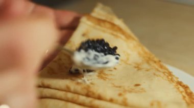 Krep üzerine taramasalata katılmış siyah balık yumurtası yaymak. İzole edilmiş yakın çekim makro. 4K video.
