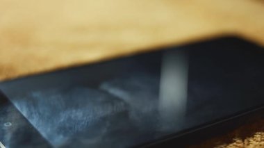 Bir yüzeyde duran akıllı telefonun makro görüntüsü. Deli biri sert bir objeyle ekranı kırıyor. Bozuk akıllı telefon. 4K video.