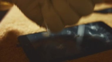 Bir yüzeyde duran akıllı telefonun makro görüntüsü. Deli biri sert bir objeyle ekranı kırıyor. Bozuk akıllı telefon. 4K video.