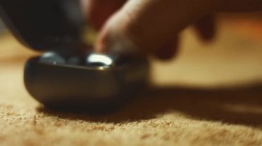 Şarj çantasındaki kablosuz kulaklıkların makro görüntüsü. Erkekler bir kulaklığı davadan alıp gösteriyorlar. 4K video.