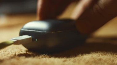 Şarj çantasındaki kablosuz kulaklıkların makro görüntüsü. Erkekler bir kulaklığı davadan alıp gösteriyorlar. 4K video.