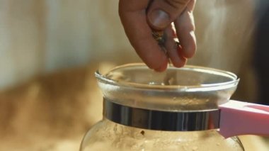 Sıcak suyla şeffaf bir fincana çay yaprakları ve çiçekler dökmek. Sri Lanka 'dan gelen aromatik ve rahatlatıcı çay hazırlanıyor. Sağlıklı yaşam tarzı kavramı. 4K video.