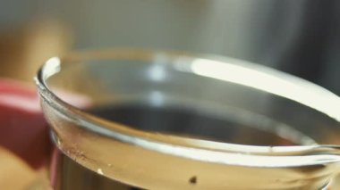 Sıcak suyla şeffaf bir fincana çay yaprakları ve çiçekler dökmek. Sri Lanka 'dan gelen aromatik ve rahatlatıcı çay hazırlanıyor. Sağlıklı yaşam tarzı kavramı. 4K video.
