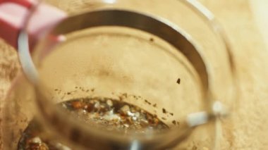 Sıcak suyla şeffaf bir fincana çay yaprakları ve çiçekler dökmek. Sri Lanka 'dan gelen aromatik ve rahatlatıcı çay hazırlanıyor. Sağlıklı yaşam tarzı kavramı. 4K video.